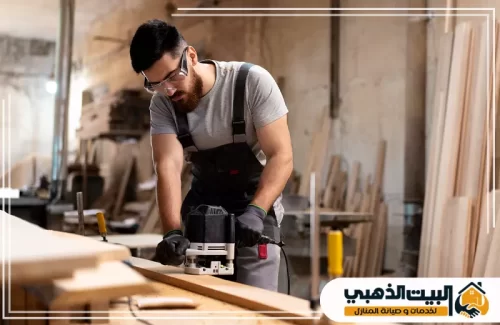 فني نجارة يستخدم آلة الراوتر الكهربائية لتشكيل الخشب، مع الالتزام التام بمعايير السلامة وارتداء النظارات.