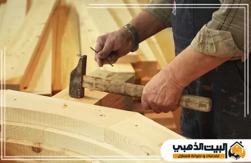 نجار يستخدم المطرقة والمسامير لتثبيت القطع الخشبية