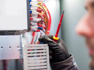 Closeup of electrician engineer works with electric cable wires Closeup of electrician engineer works with electric cable wires of fuse switch box. Electrical equipment